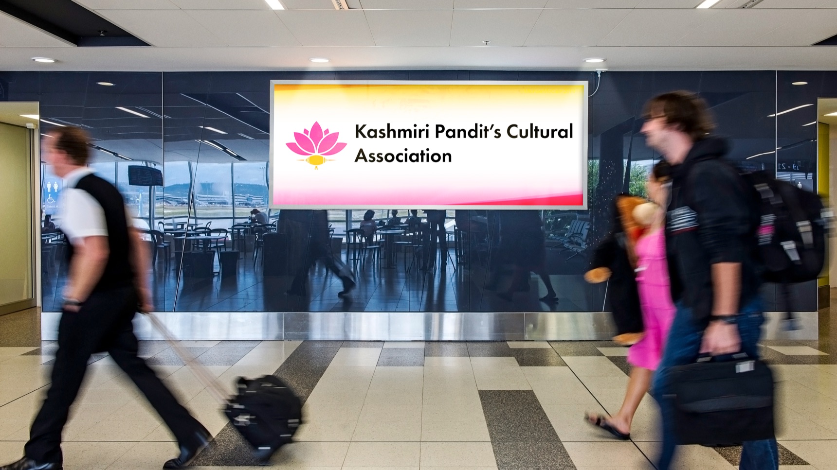 KPCA display in an airport terminal with travellers walking past
