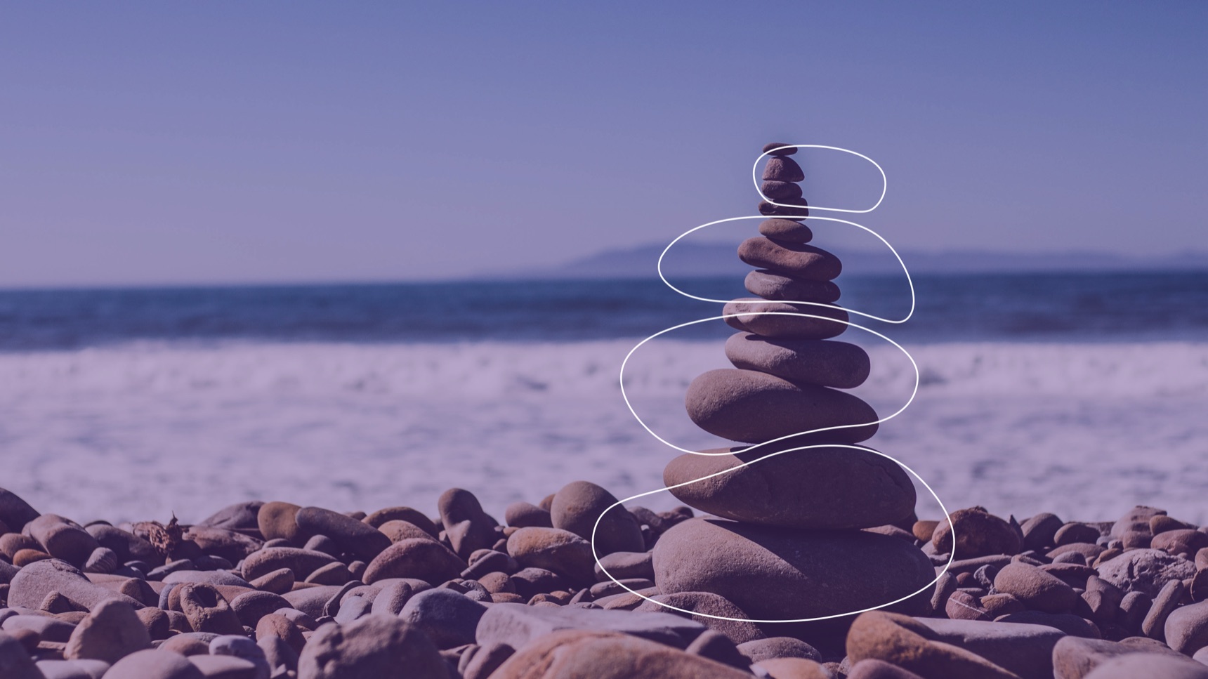 A cairn of balanced stones on a beach under a violet wash, with four hand-drawn outlines tracing the stones of the OurKarma mark